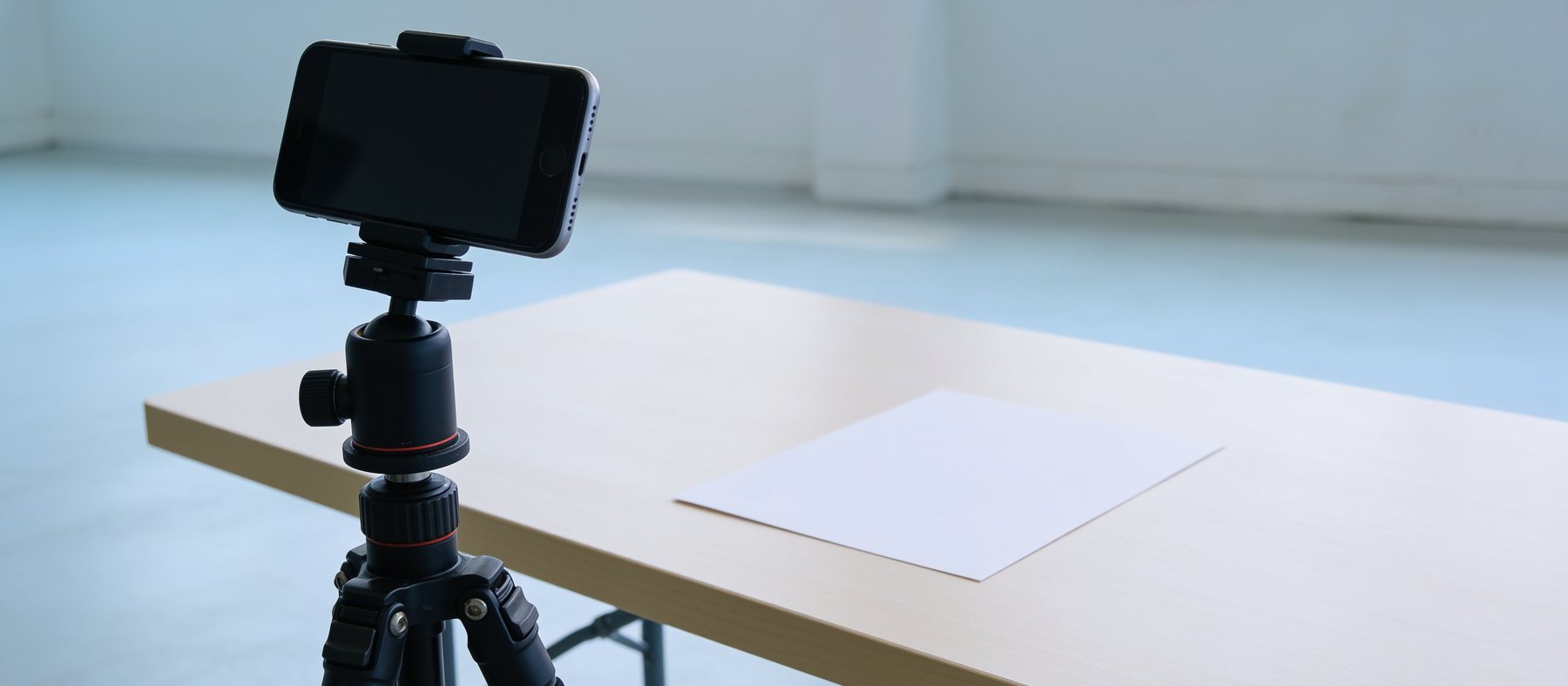 Smartphone auf einem kleinen Stativ beim Abfotografieren eines Dokuments auf einem hellen Tisch